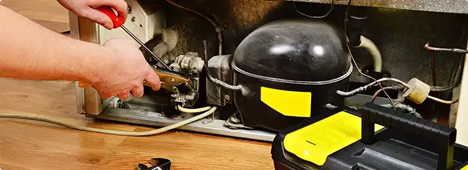 Refrigerator repair technician fixing the compressor and wiring in Medical Lake, WA
