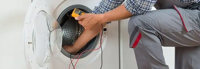Dryer repair technician inspecting and repairing a clothes dryer in Spokane, WA
