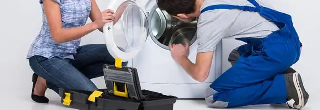 Washer repair technician inspecting a front-load washing machine with tools in Spokane, WA