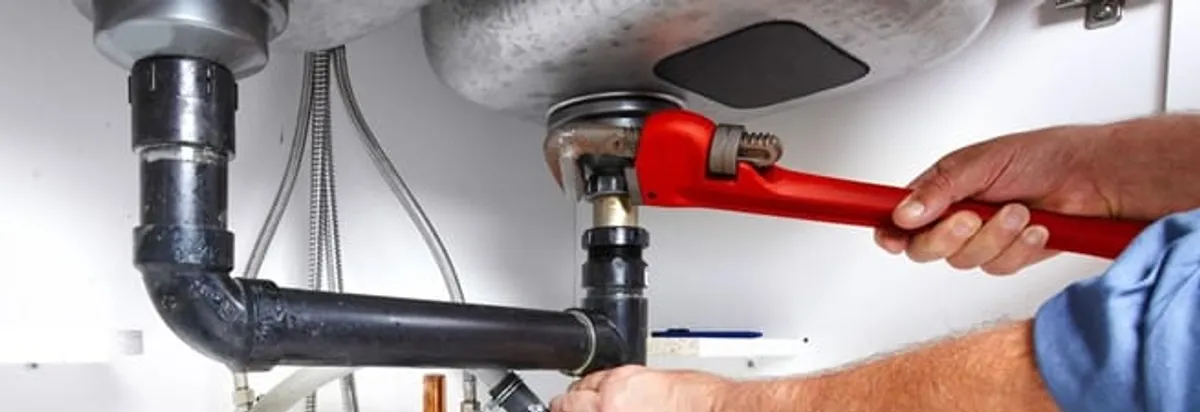 Garbage disposal repair technician tightening the sink drain and disposal connection in Spokane, WA