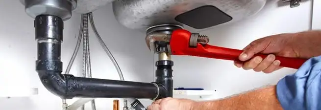 Garbage disposal repair technician tightening the sink drain and disposal connection in Spokane, WA