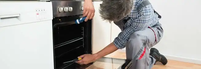 Oven repair technician inspecting and servicing an electric oven in Spokane, WA