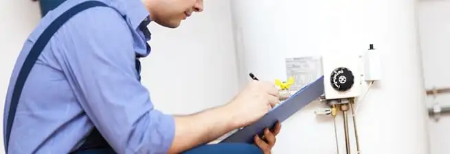 Water heater repair technician inspecting the unit and recording service notes in Spokane, WA