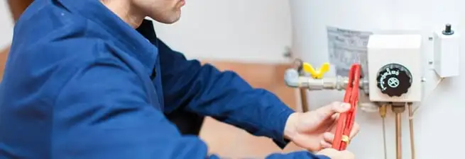 Water heater repair technician adjusting the temperature control and gas valve in Spokane, WA